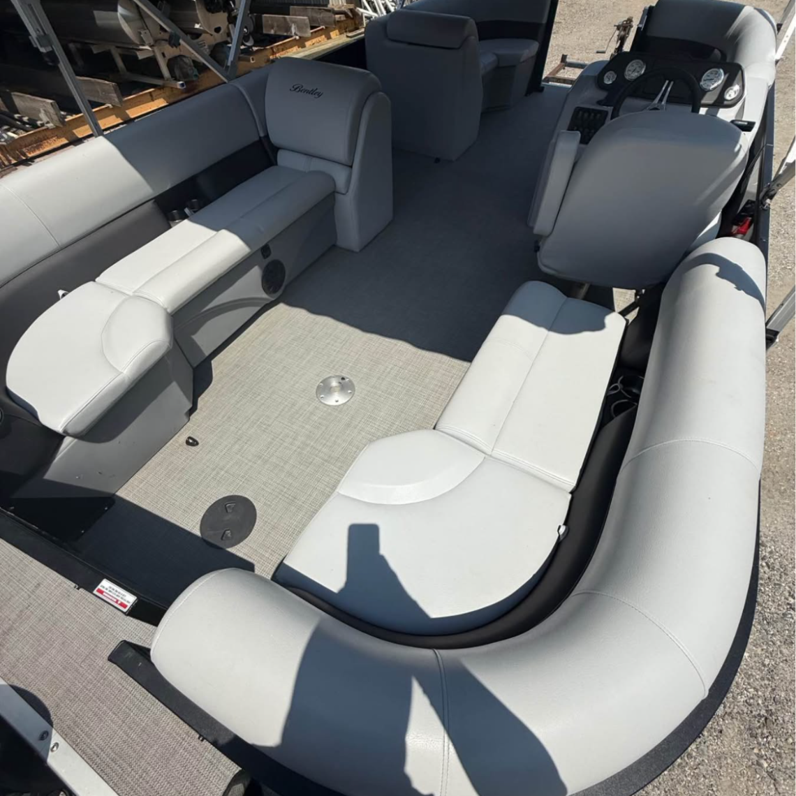 Interior of a pontoon boat with curved seating and gray cushions.